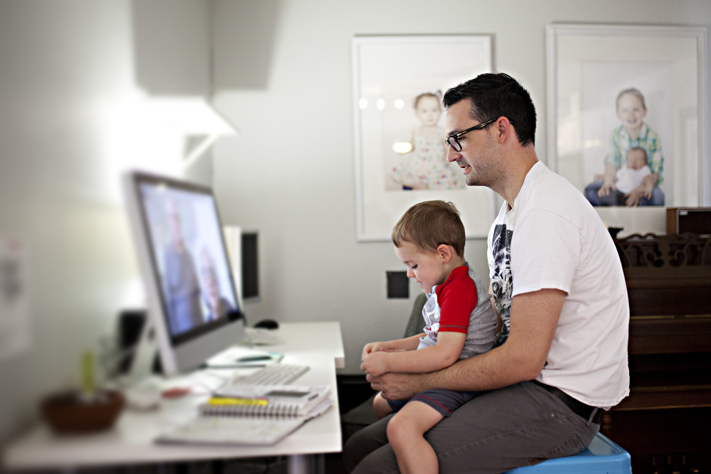 Man working from home with his child sat on his lap